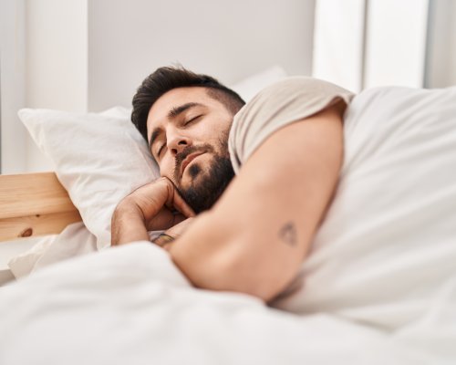 Young hispanic man sleeping on bed at bedroom