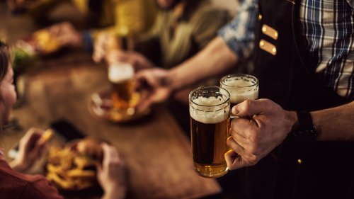 Close-up of waiter serving beer to customers in a pub.