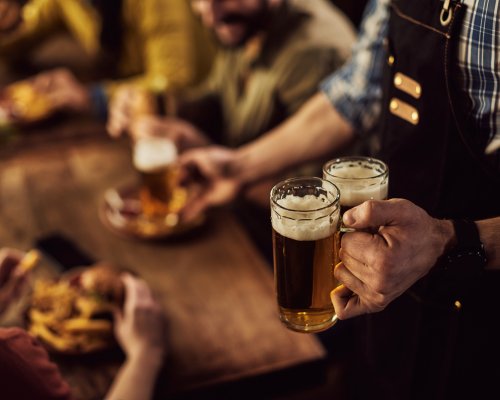 Close-up of waiter serving beer to customers in a pub.