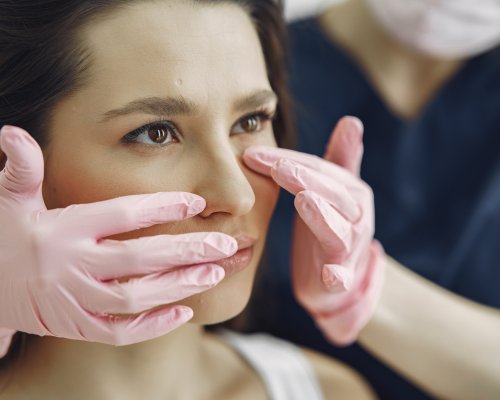 Cosmetologist holds hands near client's face. Woman with cosmetologist. Lady in a beauty studio.