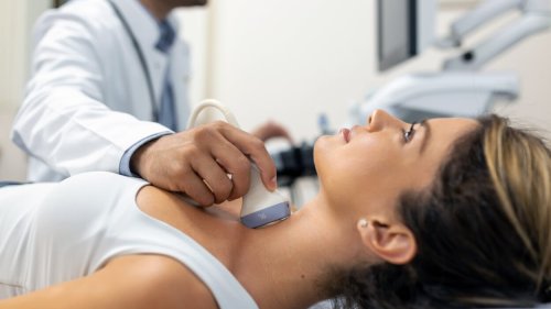 Close up shot of young woman getting her neck examined by doctor using ultrasound scanner at modern clinic