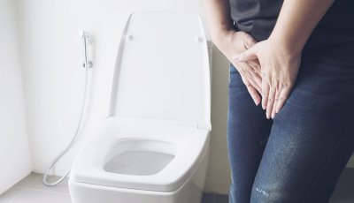 Woman holding hand near toilet bowl - health problem concept