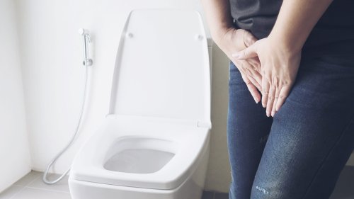 Woman holding hand near toilet bowl - health problem concept