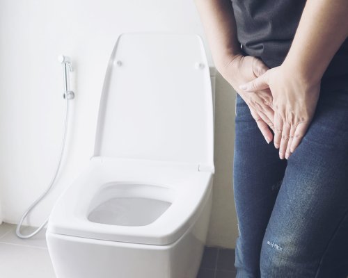 Woman holding hand near toilet bowl - health problem concept