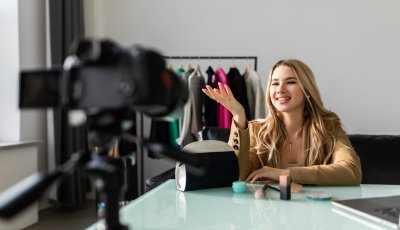 Famous blogger recording vlog at home. Young attractive woman fashion vlogger talking to the camera about her new makeup bag and cosmetics.