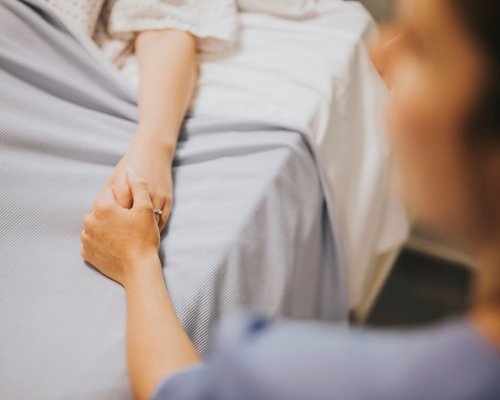 Nurse holding her patients hand