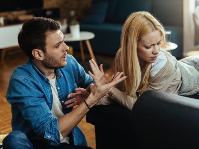 Couple with relationship difficulties having a conflict while talking in the living room.