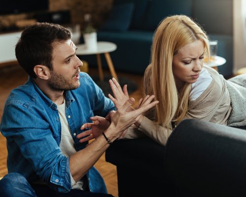 Couple with relationship difficulties having a conflict while talking in the living room.